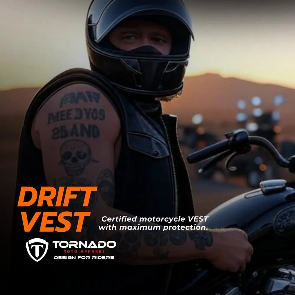 Person wearing a black motorcycle vest with tattoos, standing next to a motorcycle with a sunset background.